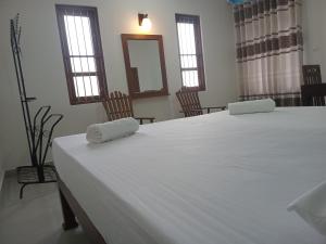 a bedroom with a large white bed with two towels on it at Mihinsa Guest in Kosgoda