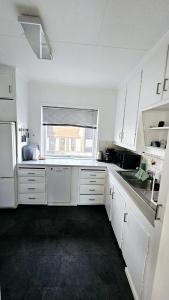 a white kitchen with a sink and a window at Koselig leilighet med balkong og parkering. in Stavanger