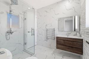 a white bathroom with a shower and a sink at Beach Revival - Clarks Beach Holiday Home in Clarks Beach +16 photos