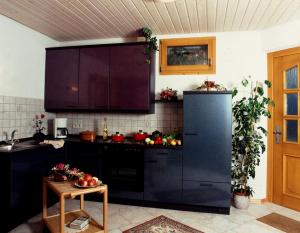 a kitchen with a black refrigerator and a table at Café Pension Waldfrieden in Bad Peterstal-Griesbach