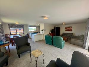 een woonkamer met banken en stoelen en een keuken bij 66 Conical Hill Road in Hanmer Springs
