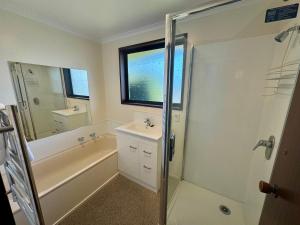 een badkamer met een bad, een wastafel en een douche bij 66 Conical Hill Road in Hanmer Springs +15 foto's