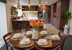 a dining room table with a vase of flowers on it at Elite Escape Hawera in Hawera