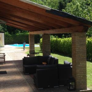 a pavilion with couches and a pool in the background at Camere con piscina Tenuta BRICCHETTO in Castagneto Po