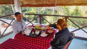 a man and woman sitting at a table eating food at Green Wood Hotel in Ella