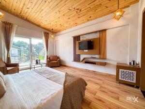 a bedroom with a bed and a tv on the wall at Wonderwood Corbett Resort -1min walk to River with Deep Jungle Trail in Rāmnagar