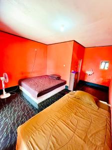 龙目岛库塔Perwita Homestay的一间卧室设有两张床,拥有橙色的墙壁。