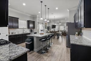 a kitchen with black cabinets and a kitchen island with bar stools at Zen House, a peaceful sanctuary in Shreveport, LA! Tv in each room in Shreveport +37 photos