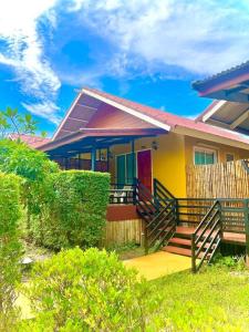 une maison jaune avec un porche et une clôture dans l'établissement Lanta For Rest Boutique, à Ko Lanta