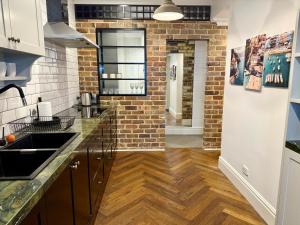 a kitchen with wooden floors and a brick wall at Cronulla Beach Escape - Walk To Beach - Parking in Cronulla