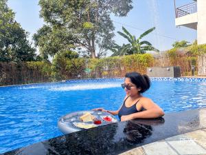 a woman in a swimming pool with a tray of food at Wonderwood Corbett Resort -1min walk to River with Deep Jungle Trail in Rāmnagar