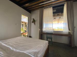 ein Schlafzimmer mit einem Bett, einem Fenster und einem Stuhl in der Unterkunft Himori homestay & coffee in Ấp Kim Thạch