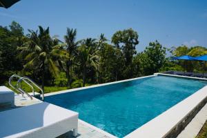 a swimming pool in a resort with trees in the background at DKelingking Secret Villas in batumadeg