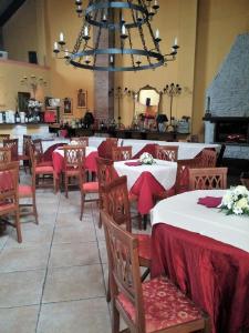 uma sala de jantar com mesas e cadeiras e um lustre em Hotel Damian Park Hotel Delle Magnolie em Trofarello