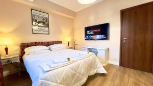 a bedroom with a white bed with a tv on the wall at Bellaria Casa Indipendente-Giardino Privato-Parcheggio Privato-Strategic Location 5 Terre-Portofino in Rapallo