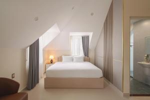 a bedroom with a white bed and a window at The One Da Lat Hotel in Da Lat +42 photos