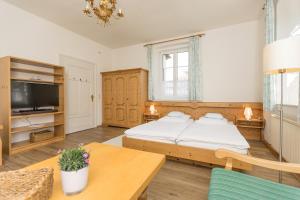 1 dormitorio con cama, mesa y TV en Villa Waldfrieden - Ferienwohnungen und -Haus en Kochel