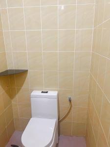 a bathroom with a toilet and a tiled wall at Queen room with private bathroom in Kuala Terengganu