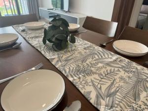 a table with white plates and a table cloth with a plant at Gem Suites Kuching at 5 pax in Kuching