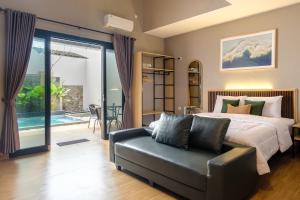 a bedroom with a bed and a couch and a patio at Calma Jawon Villa Jogja in Piyungan +24 photos