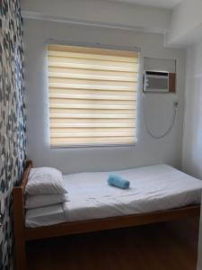 a bed in a room with a window with a pillow at 2br Condotel in Camella Northpoint in Davao City