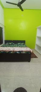 a bed in a room with a green wall at Shri Raameshvaram vidya vila in Ayodhya