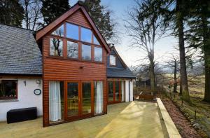 a house with glass doors and a wooden deck at Brae House in Aberfeldy