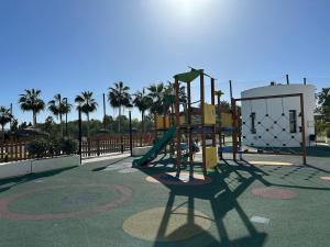 a playground with a slide in a park with palm trees at Apartamento Playa Granada Golf in Motril