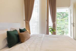 a bedroom with a white bed with a window at Calma Edelweiss Villa Lawang Malang in Malang
