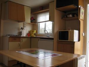 a kitchen with a wooden table and a microwave at Le Marverand in Saint-Julien