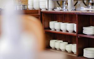 een plank vol witte kommen en borden bij Xavia Hotel in Quy Nhon