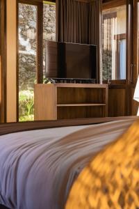 a bedroom with a bed with a flat screen tv at Shankara Munduk Bali in Munduk