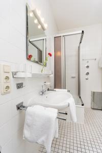 a white bathroom with a sink and a shower at Villa Waldfrieden - Ferienwohnungen und -Haus in Kochel