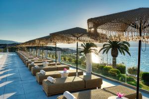 a row of chairs on a resort with the ocean at Proteas Blu Resort in Pythagoreio