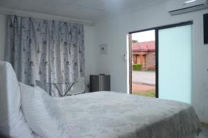 a bedroom with a bed and a large window at Alldays Sunset Lodge in Alldays