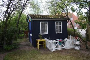a blue tiny house with a white fence at Stor villa med privat have in Bredebro