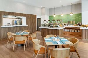 a restaurant with tables and chairs and a kitchen at Hilton Garden Inn San Jose Airport City Mall in Alajuela City
