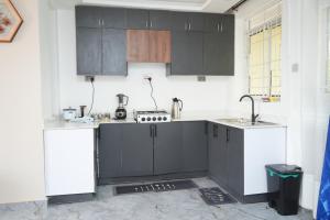 a kitchen with black and white cabinets and a sink at E-Residences in Gulu +9 photos