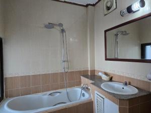 a bathroom with a tub and a sink and a shower at Thavisouk Hotel, Vang Vieng in Vang Vieng