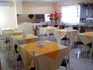 Estação Hotel في Castanhal: غرفة مع طاولات وكراسي مع قماش الطاولة الأصفر والأبيض