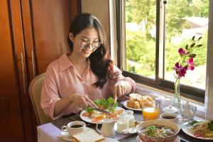 Una donna seduta a un tavolo con un piatto di cibo di Pink Boutique Ben Thanh Hotel ad Ho Chi Minh