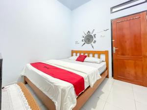 a bedroom with a bed and a wooden door at RedDoorz Syariah at Home Ampana Guest House Ampana Kota in Dondo