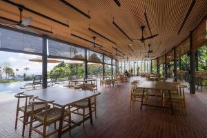 un ristorante vuoto con tavoli, sedie e finestre di Vanavasa Resort a Bentong Altre 10 foto