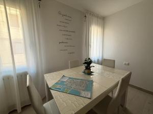 a white dining room table with chairs and a menu on the wall at Suite Piazzetta Vigo in Chioggia