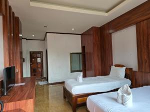 a hotel room with two beds and a flat screen tv at Thavisouk Hotel, Vang Vieng in Vang Vieng