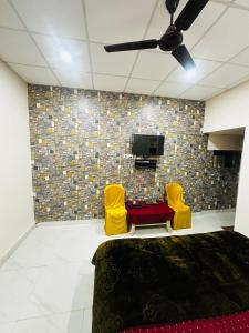 a living room with two yellow chairs and a tv at Hotel Tathastu in Rāmtek