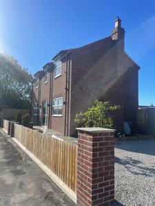 a brick house with a fence in front of it at Newton house in Burton Fleming