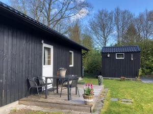 un pequeño cobertizo negro con mesa, sillas, mesa y silla en Bungalow Lijsterbes | 4 personen - Vakantiepark De Kremmer, en Gasselte