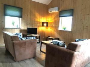 Una sala de estar con dos sofás y un televisor. en Bungalow Lijsterbes | 4 personen - Vakantiepark De Kremmer, en Gasselte