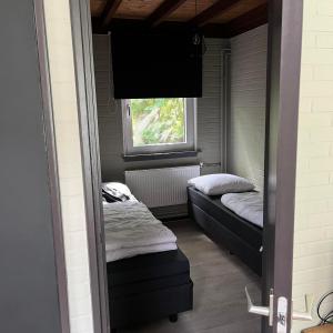 two beds in a small room with a window at Bungalow Zandzegge | 4 personen - Vakantiepark De Kremmer in Gasselte